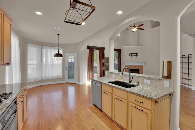 kitchen with light wood-type flooring, stainless steel appliances, sink, light brown cabinets, and ceiling fan