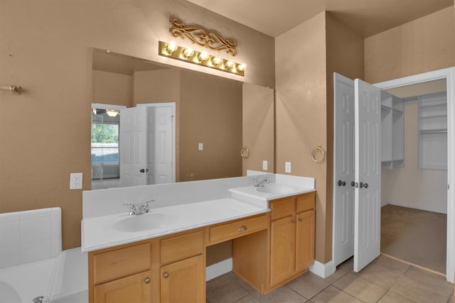 bathroom with tile patterned floors, a washtub, and vanity