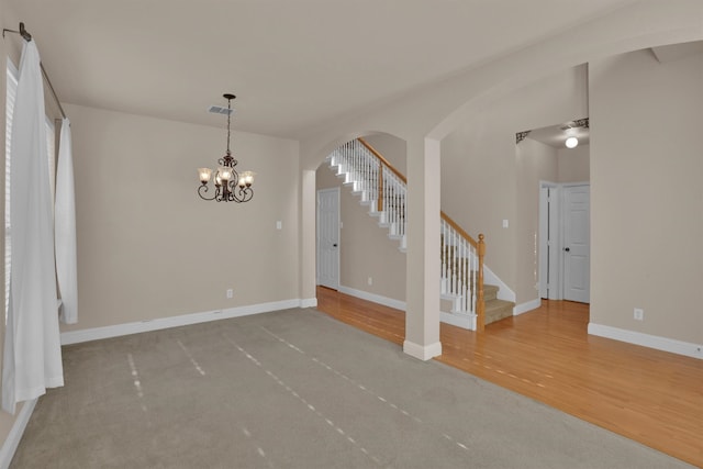 interior space with light wood-type flooring and ceiling fan with notable chandelier