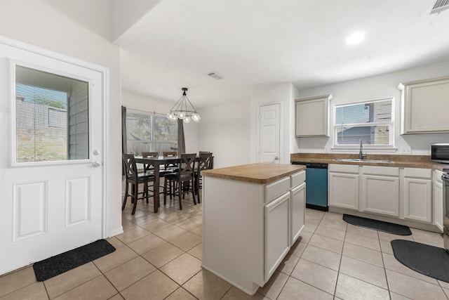 kitchen with sink, hanging light fixtures, a kitchen island, appliances with stainless steel finishes, and light tile patterned floors