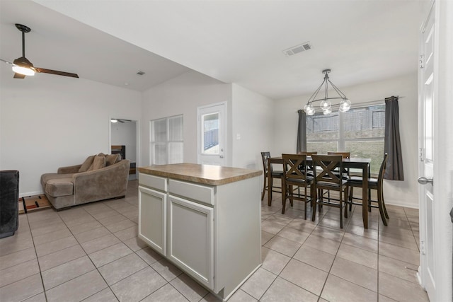 kitchen featuring white cabinets, light tile patterned floors, a kitchen island, decorative light fixtures, and ceiling fan with notable chandelier