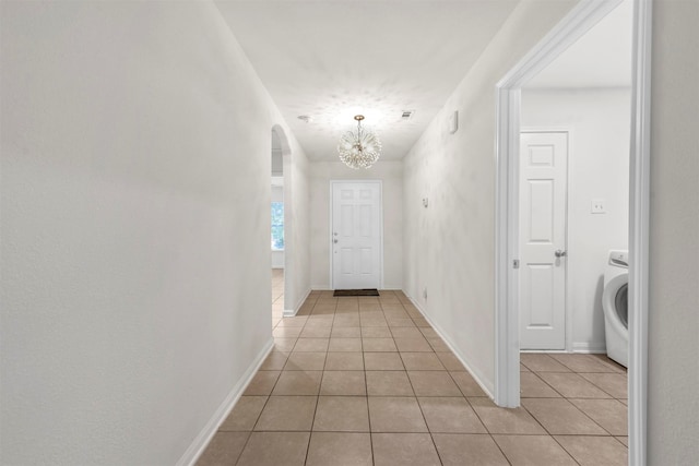 entryway featuring light tile patterned floors, washer / dryer, and a notable chandelier