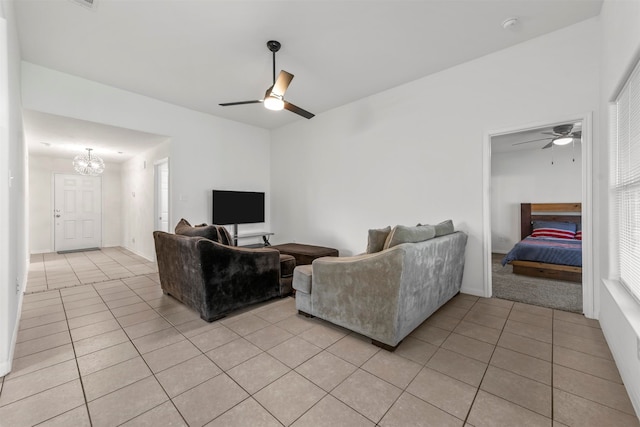 tiled living room with ceiling fan with notable chandelier