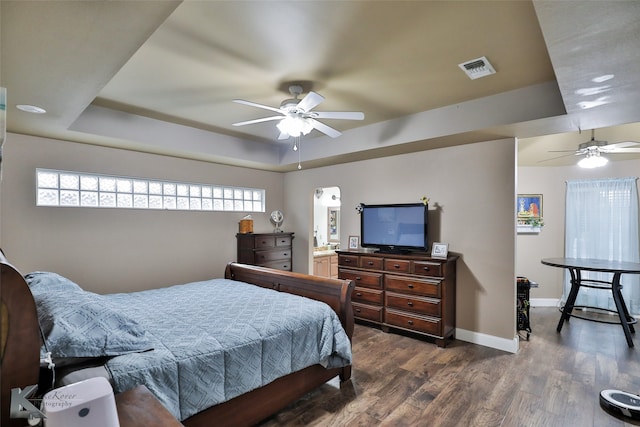 bedroom featuring multiple windows, ceiling fan, a raised ceiling, and dark hardwood / wood-style flooring