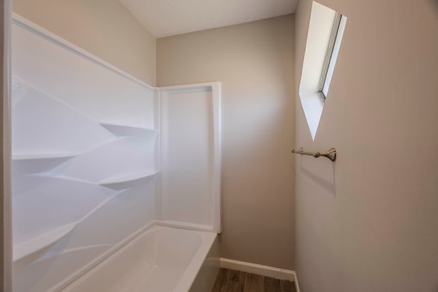 bathroom with hardwood / wood-style flooring, a tub to relax in, and a textured ceiling