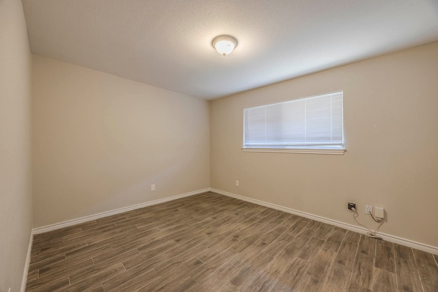 empty room with a textured ceiling and dark wood-type flooring