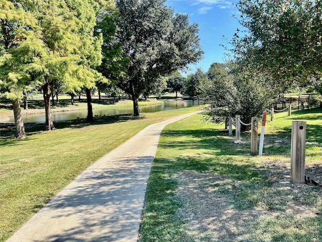 view of property's community with a lawn and a water view