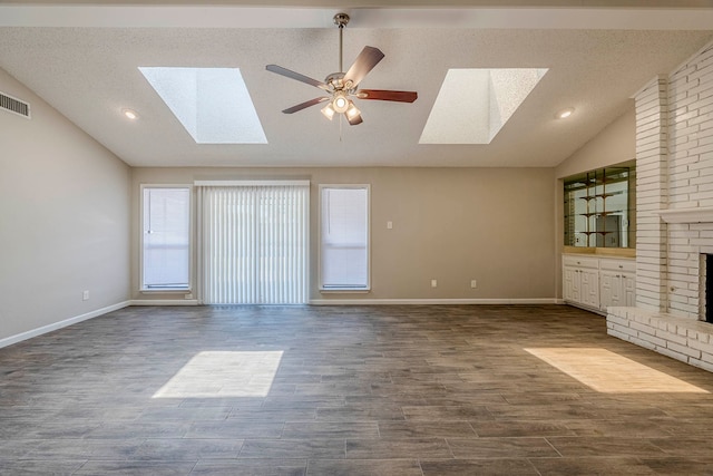 unfurnished living room featuring a textured ceiling, lofted ceiling with skylight, ceiling fan, a fireplace, and dark hardwood / wood-style floors