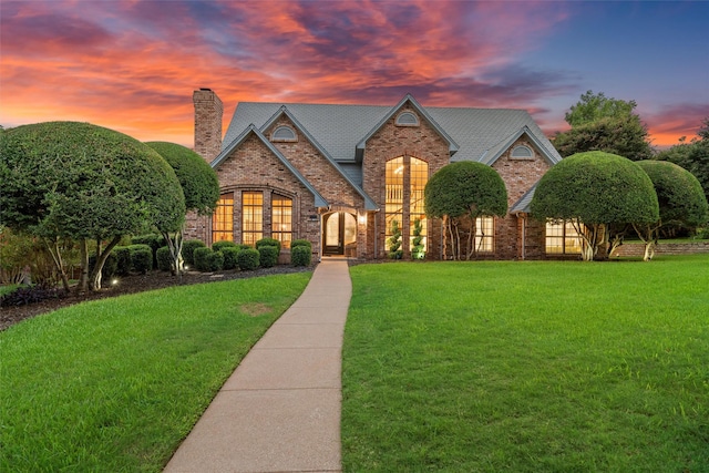 view of front of property with french doors, a front lawn, a chimney, and brick siding