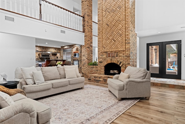 living room featuring a high ceiling, hardwood / wood-style floors, and a brick fireplace