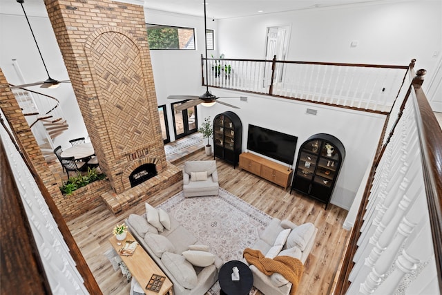 unfurnished living room with light hardwood / wood-style flooring, ceiling fan, a towering ceiling, and a fireplace