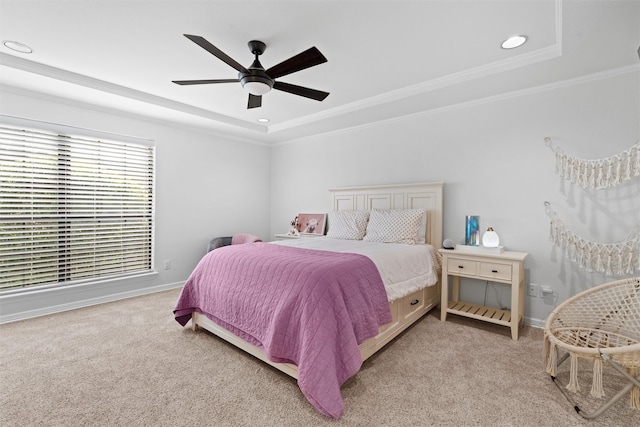 carpeted bedroom with a tray ceiling, ornamental molding, and ceiling fan