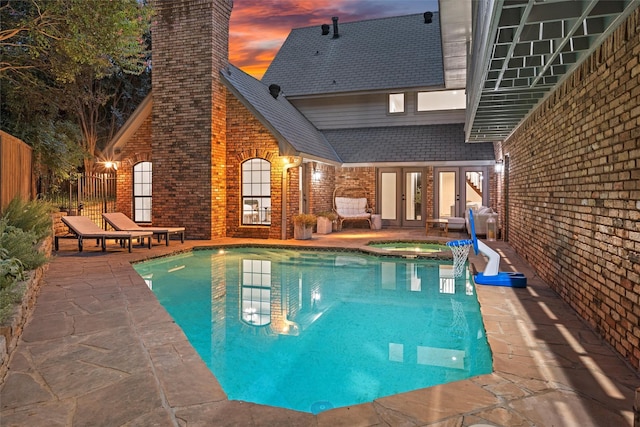 outdoor pool with fence, french doors, a patio, and an in ground hot tub