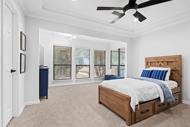 bedroom with crown molding, light colored carpet, a tray ceiling, and ceiling fan