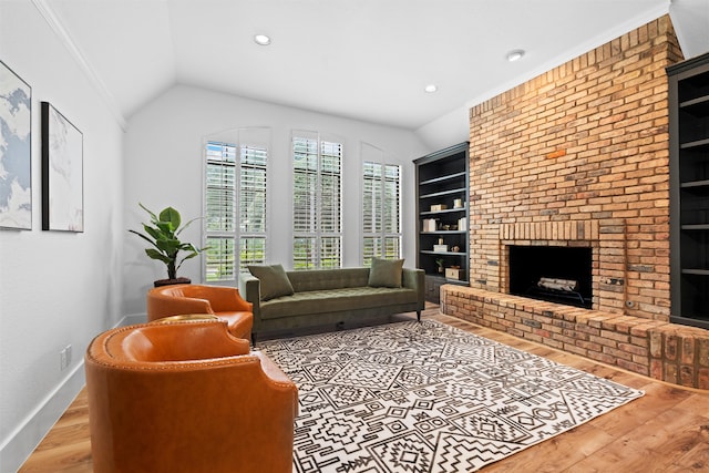 living room featuring hardwood / wood-style floors, built in shelves, ornamental molding, a brick fireplace, and lofted ceiling