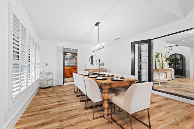 dining space with light wood-type flooring, sink, and ornamental molding