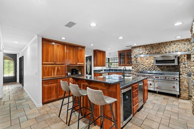 kitchen featuring ornamental molding, a kitchen bar, wine cooler, double oven range, and an island with sink