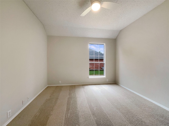 spare room with light colored carpet, vaulted ceiling, a textured ceiling, and ceiling fan