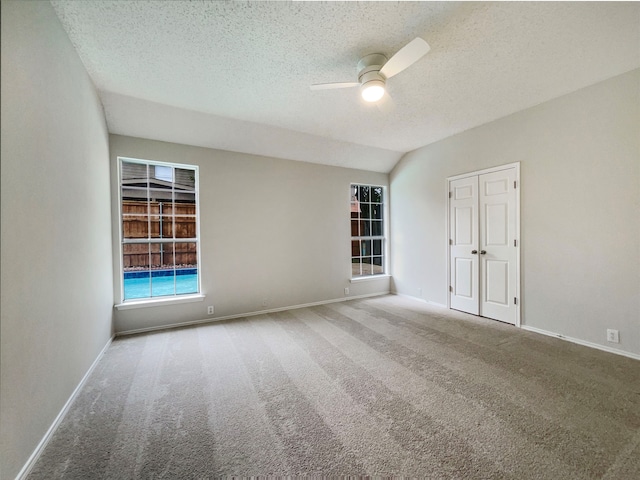 unfurnished room with carpet flooring, ceiling fan, lofted ceiling, and a textured ceiling