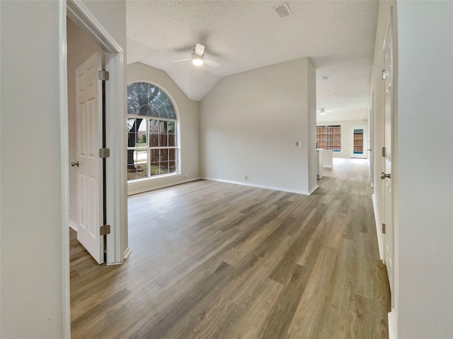 empty room featuring hardwood / wood-style floors, ceiling fan, a textured ceiling, and vaulted ceiling