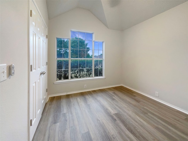 spare room featuring lofted ceiling and hardwood / wood-style flooring