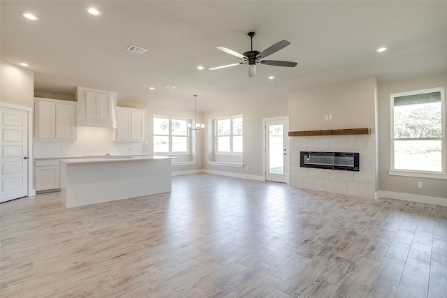 unfurnished living room with a tile fireplace, a healthy amount of sunlight, and light hardwood / wood-style flooring