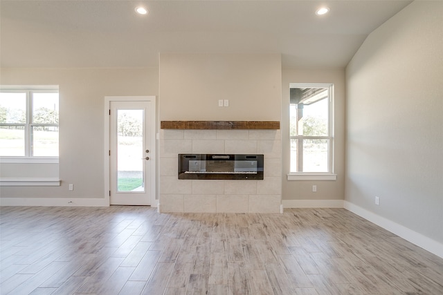 unfurnished living room featuring a fireplace, a wealth of natural light, and light hardwood / wood-style floors