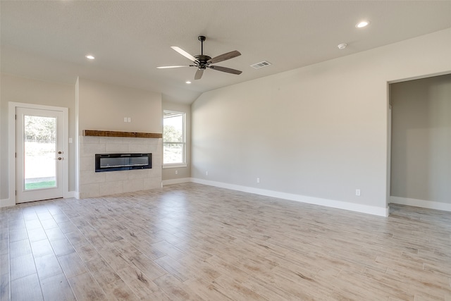 unfurnished living room with a wealth of natural light, a tile fireplace, ceiling fan, and light hardwood / wood-style flooring