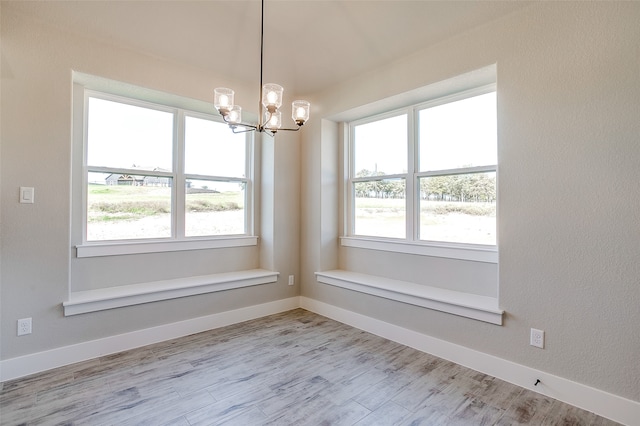 unfurnished dining area with a chandelier, a wealth of natural light, and light hardwood / wood-style flooring