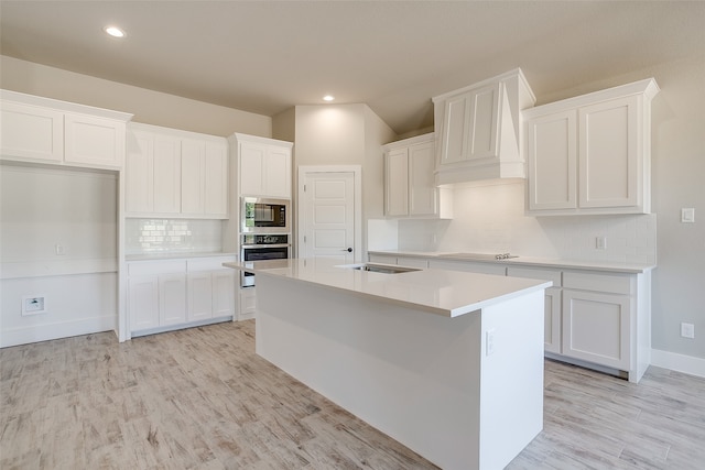 kitchen featuring white cabinetry, custom range hood, stainless steel appliances, and a center island with sink