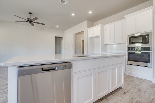 kitchen featuring light hardwood / wood-style floors, a kitchen island with sink, ceiling fan, white cabinetry, and appliances with stainless steel finishes