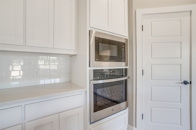 kitchen with backsplash, white cabinets, and stainless steel appliances