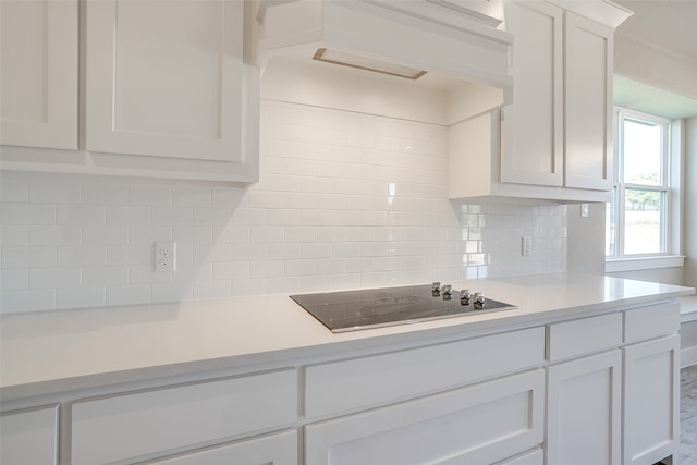 kitchen featuring white cabinetry, black electric stovetop, and decorative backsplash