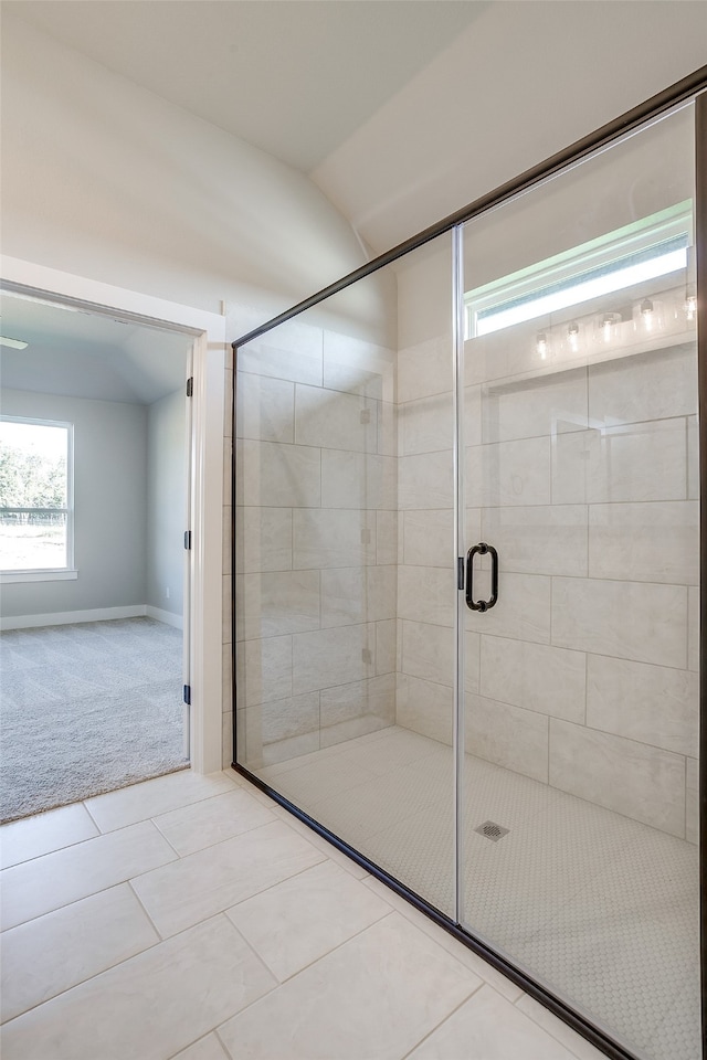 bathroom featuring a shower with shower door, tile patterned floors, and vaulted ceiling