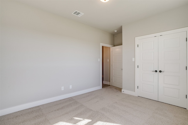 unfurnished bedroom featuring light colored carpet and a closet