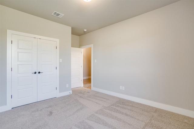 unfurnished bedroom with a closet and light colored carpet