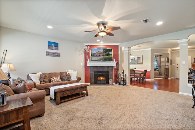 living room with ornate columns, ceiling fan, crown molding, wood-type flooring, and a tiled fireplace