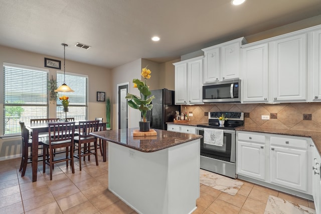 kitchen featuring decorative backsplash, stainless steel appliances, pendant lighting, a center island, and white cabinetry