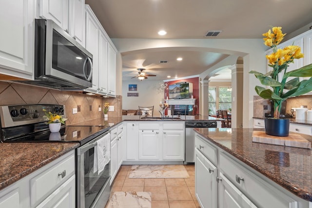 kitchen featuring dark stone counters, ceiling fan, ornate columns, appliances with stainless steel finishes, and white cabinetry