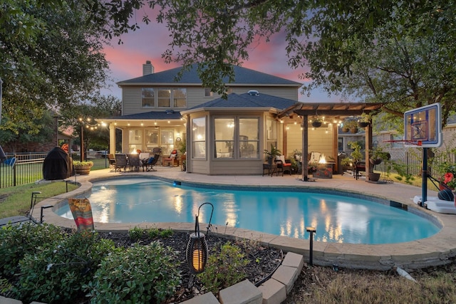 pool at dusk with a pergola and a patio