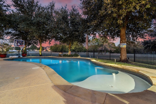 pool at dusk with a patio area