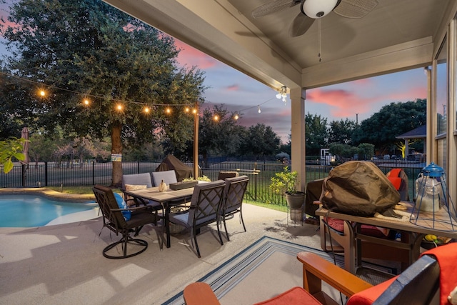 patio terrace at dusk featuring ceiling fan and a fenced in pool