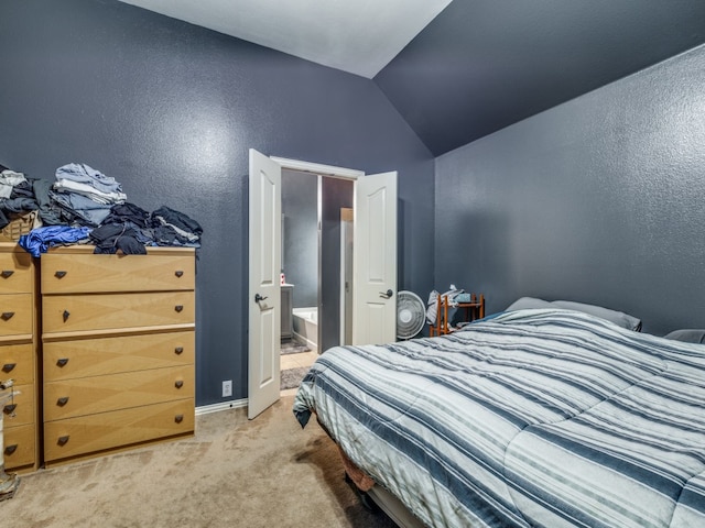 bedroom with carpet flooring, vaulted ceiling, and ensuite bath