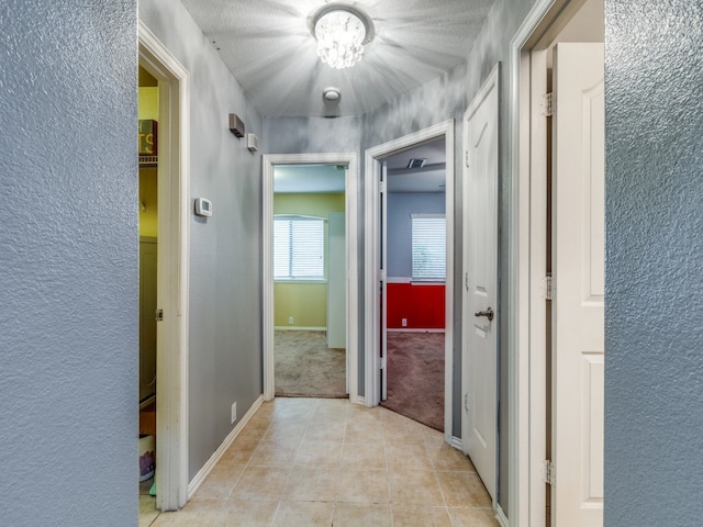 hallway with a textured ceiling and light tile patterned flooring