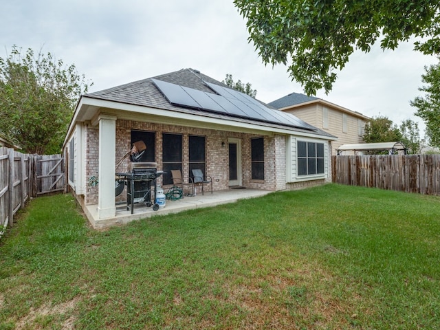 rear view of house with a lawn, solar panels, and a patio area