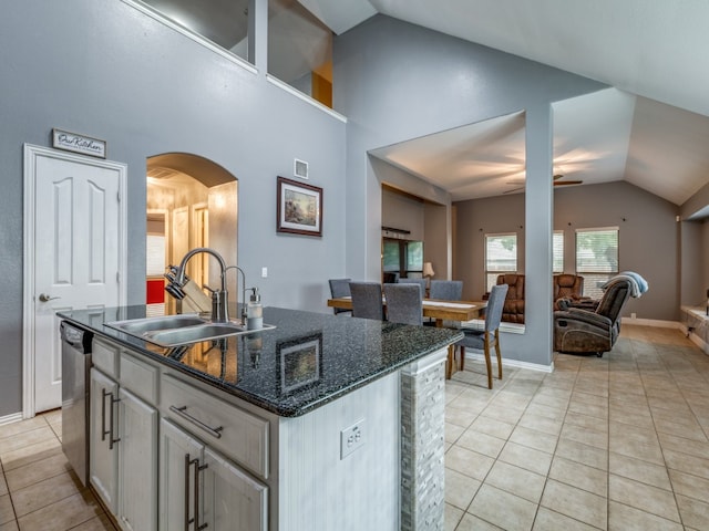 kitchen featuring dark stone counters, light tile patterned floors, sink, ceiling fan, and vaulted ceiling