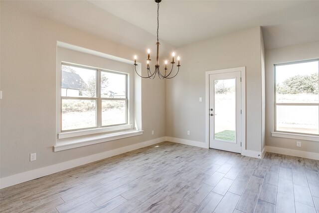 unfurnished dining area with light hardwood / wood-style floors, a healthy amount of sunlight, and an inviting chandelier