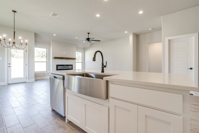 kitchen featuring a center island with sink, dishwasher, white cabinets, hanging light fixtures, and sink