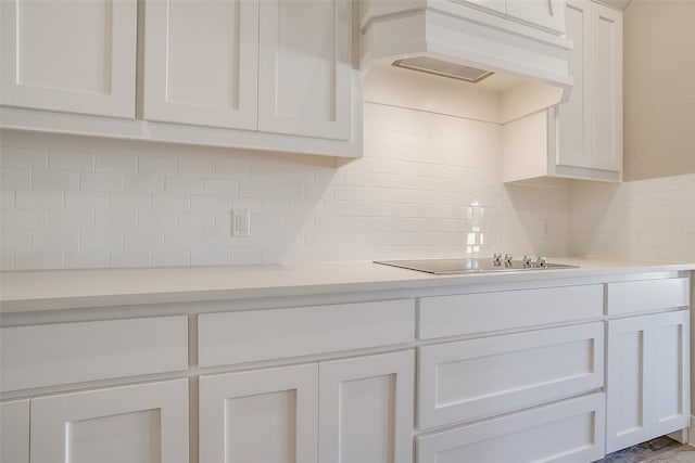 kitchen featuring white cabinets, exhaust hood, black electric cooktop, and tasteful backsplash