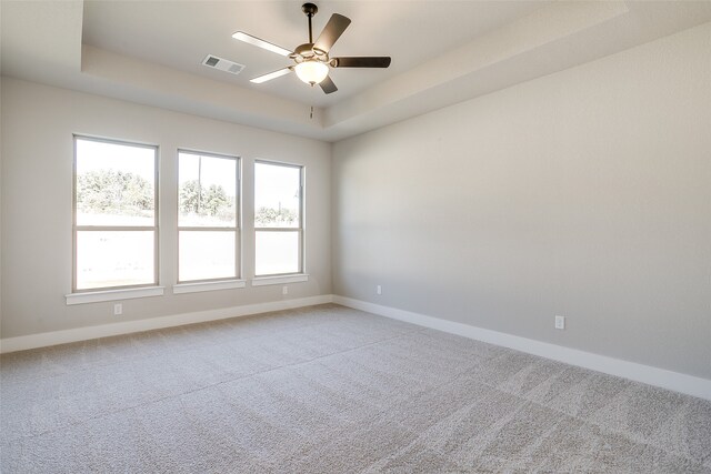 carpeted empty room with a tray ceiling and ceiling fan